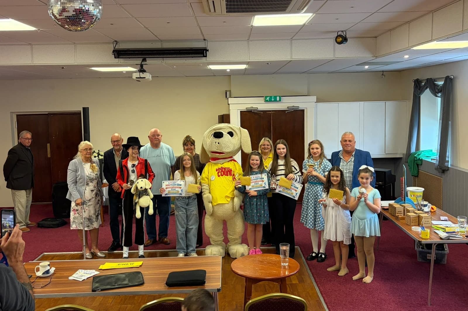 Winners of the Kindness Counts UK talent show final holding their certificates and trophies, with Nic the mascot and the judges.
