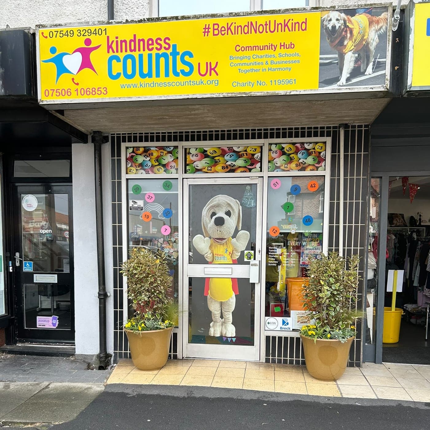The Kindness Counts UK hub on Victoria Road West, with Nic the puppy standing in the doorway.