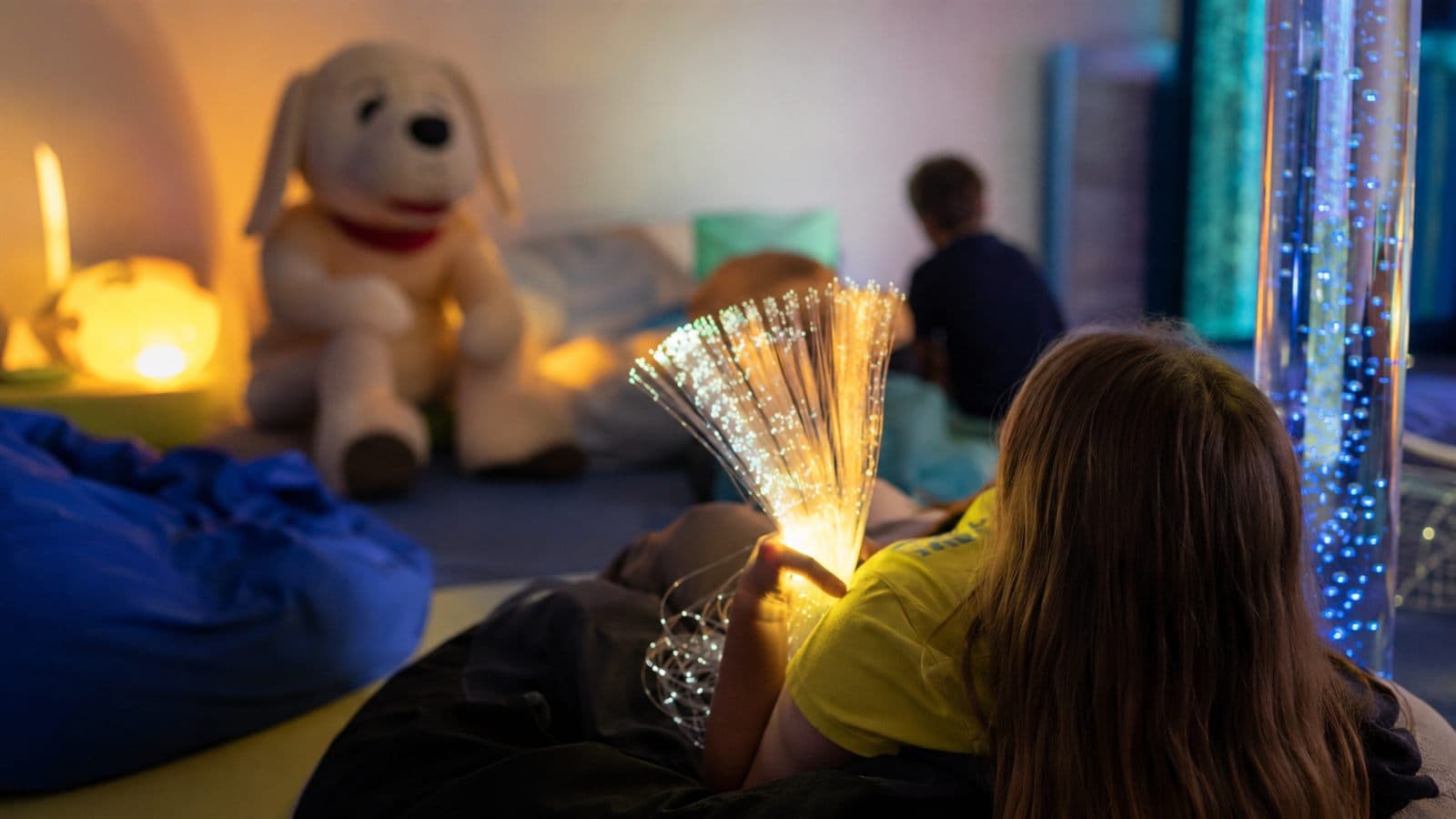 A calm sensory room with soft coloured lighting.