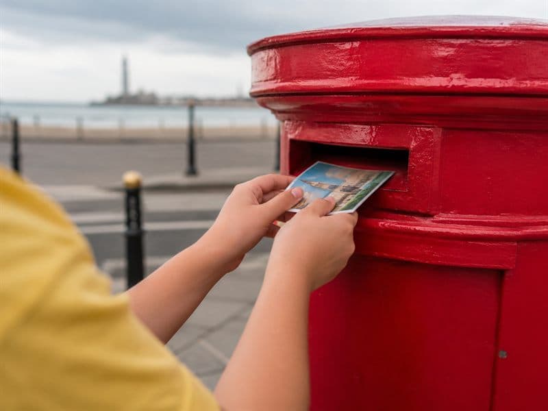 A child posting a kindness postcard into a brightly painted box.